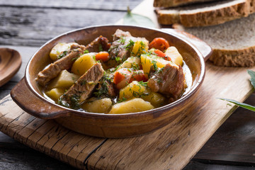 Irish dinner. Beef meat stewed with potatoes, carrots and soda bread on wooden background, top...