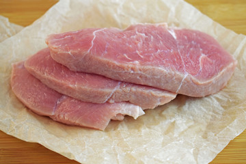 A piece of fresh meat on paper, on a wooden Board.