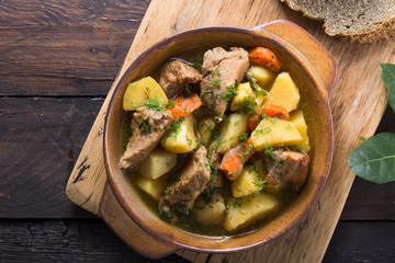 Irish dinner. Beef meat stewed with potatoes, carrots and soda bread on wooden background, top...