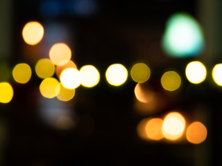 Dark urban background with defocused bulbs. White and golden blurry spots