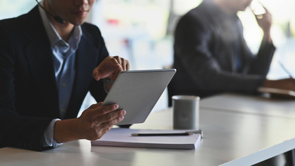 Cropped shot of young smart man working as call-center and giving information to his customer while sitting at the working desk next to his colleague.