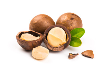 Macadamia nut with pieces and green leaves isolated on a white background