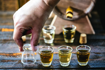 Hand holding glass of alcoholic drinks, cachaça, pinga, rum and cognac. Selection of strong and hard alcoholic drinks, glasses. Vodka, cognac, whiskey, grappa, liqueur, vermouth, rum. Space for text.