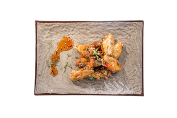 Fried Chicken Wings with chili pepper on grey plate isolated on white background