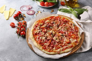 Italian cuisine. Pizza on a white and gray background. Cooking process. Fresh vegetables and basil. background image, copy space, pizza with hands.