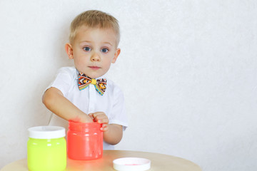 A little toddler boy is intently playing with slime, a sensory play aimed at developing fine motor skills in young children and a fun activity 