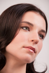 Fototapeta premium Close up face of a young woman with clean fresh skin and dark hair. Young woman looks away from the camera