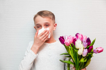 Blond boy afraiding of allergy to bouquet of tulips