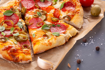 Homemade spicy pepperoni pizza and cooking ingredients. Pepperoni pizza on a gray wooden table.