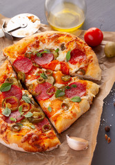Homemade spicy pepperoni pizza and cooking ingredients. Pepperoni pizza on a gray wooden table.