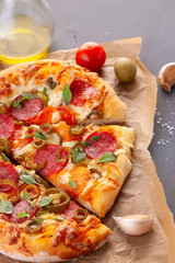 Homemade spicy pepperoni pizza and cooking ingredients. Pepperoni pizza on a gray wooden table.