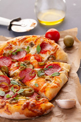 Homemade spicy pepperoni pizza and cooking ingredients. Pepperoni pizza on a gray wooden table.