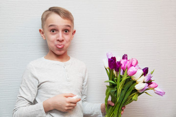 Blond boy afraiding of allergy to bouquet of tulips