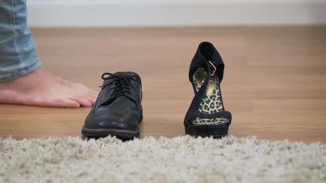 Men's boot and women's high heel shoe standing on the floor, male Caucasian feet coming up. Intersex person choosing outfit. Man and woman in one person, gender identity.