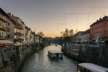 Fototapeta na wymiar Sunset over the city of Ljubljana, capital of Slovenia, with boat on a river