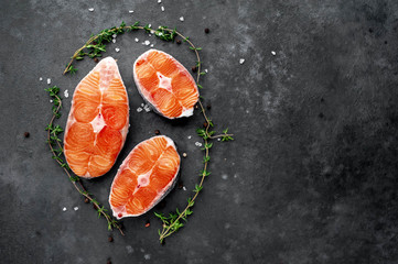 fresh raw salmon steaks on a stone background with salt, pepper, lemon with copy space for your text