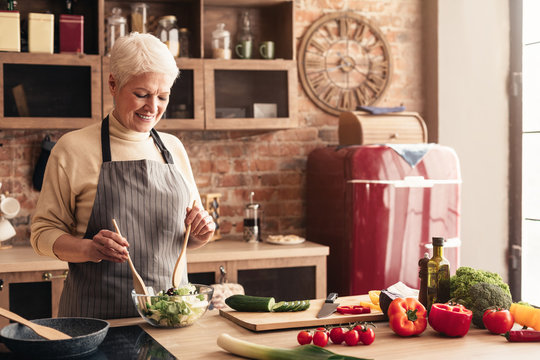 Senior Lady Cooking Fresh Salad At Home Kitchen