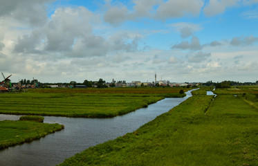 Zaanse Schans, Holland, August 2019. North-east of Amsterdam is a small community located on the quay of the Zaan river. View from above of the fields with mills, tourists are noticed. Cloudy day.