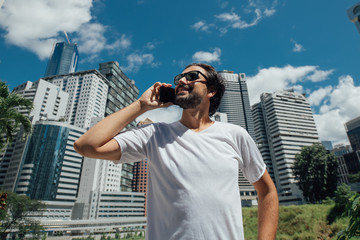 A man talks on the phone against the backdrop of skyscrapers