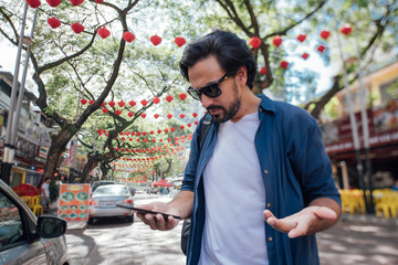 A man got lost on a Chinese street and looks at the map on the phone