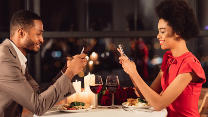 Afro Couple Using Smartphones During Romantic Date In Restaurant, Panorama