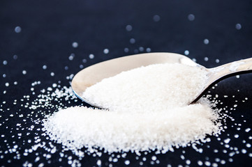 spoon with sugar on black background