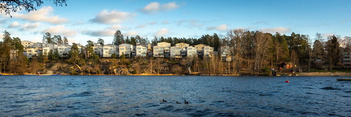 Fototapeta na wymiar Modern residence on a rocky beach. Scandinavian landscape: stone Islands covered with coniferous forest. Panoramic view of Baltic Sea bay in spring. Landscape with beautiful clouds. Header.