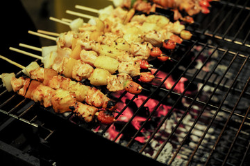Closeup row of meat bbq on the metal grill with blurred hot charcoal on the tray in background