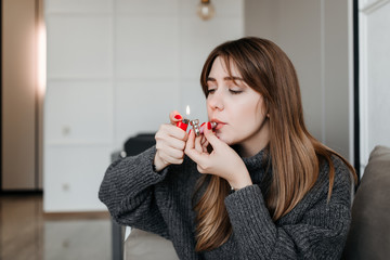 young millennial woman smoking marijuana from pipe at home in apartment