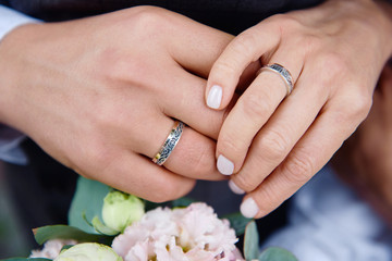 Obraz na płótnie Canvas Newlywed couple's hands with wedding rings on bridal bouquet, copy space. Wedding couple, bride and groom, hands with rings, closeup