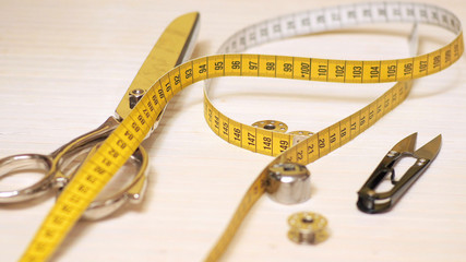 Tailor tools isolated on wooden background. Scissors, needle, Tailoring Meter, hand