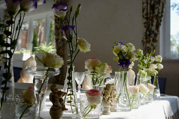 Beautiful floral arrangement on wedding table in restaurant, copy space. Bouquet of pink roses, purple eustoma and greenery in glass vases. Luxury wedding decorations