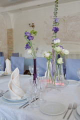 Table setting with white plates, napkins, wineglasses, cutlery and flowers on table, copy space. Place setting at wedding reception. Table served for wedding banquet in restaurant