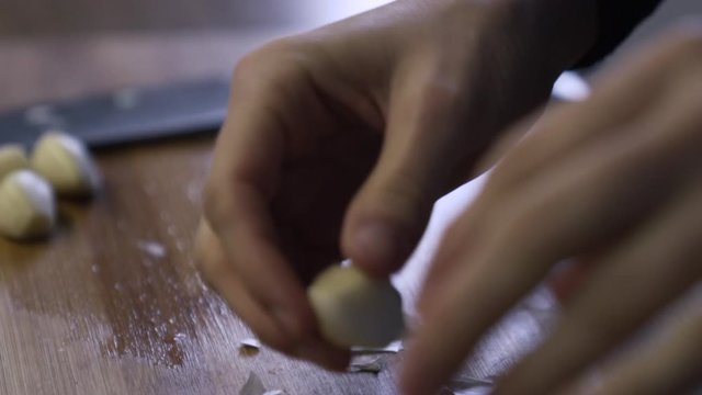Close shot as a hand peeling garlic in the kitchen
