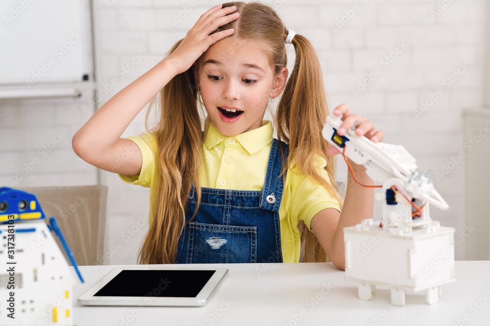 Poster Stem lesson. Surprised girl constructing diy robot at class