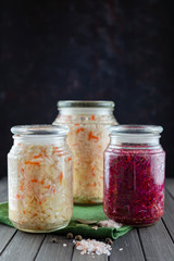 glass jars of fermented white, red cabbage, spices, salt. vegetables on a dark background. using textile green. fermentation is a source of probiotic. popular vegetarian food. copy space
