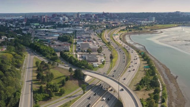 Aerial: Flying over freeway 295 looking out to downtown Portland city skyline, Maine, USA. 