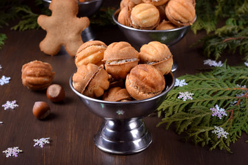 Walnut shaped shortbread cookies with cream filling in a metal cup against the dark background