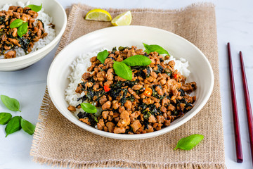 Spicy Thai Basil Chicken Stir Fry on Top of Rice in a Bowl with Chopsticks High Angle Photo.