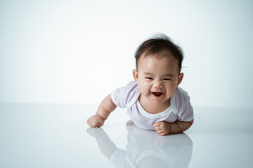 baby laying on her belly. tummy time cute baby in studio portrait on white background