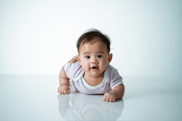baby laying on her belly. tummy time cute baby in studio portrait on white background
