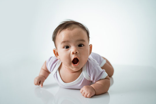 baby laying on her belly. tummy time cute baby in studio portrait on white background