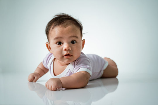baby laying on her belly. tummy time cute baby in studio portrait on white background
