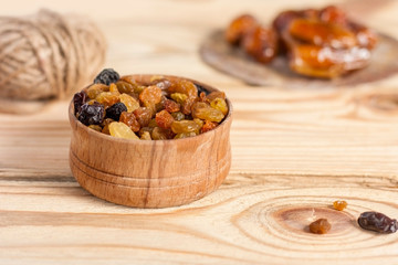 Golden raisins in a bowl on a light wooden background. Dried fruits.