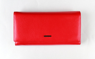 Red leather purse lies on white surface.