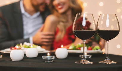 Couple enjoying romantic dinner in restaurant, selective focus on wine glasses