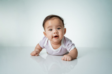 baby laying on her belly. tummy time cute baby in studio portrait on white background