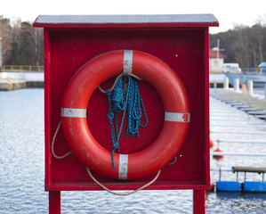 Red lifebuoy with a blue rope to save people at the sea, lake, river