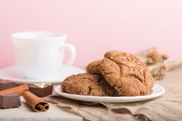 homemade oatmeal cookies with a cup of cocoa on a pink pastel background. side view, selective focus.