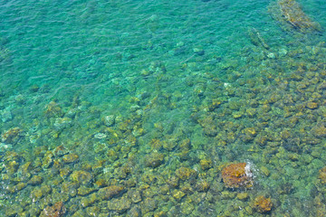 Fototapeta na wymiar Sea stones in the sea water. Pebbles under water. The view from the top. Nautical background. Clean sea water. Transparent sea.